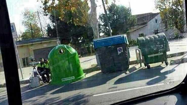 Dos agentes sitúan un radar entre contenedores de basura
