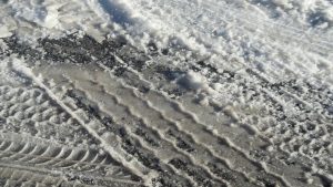 Coche circulando por carretera nevada con sal, mostrando posibles daños por corrosión y protección del vehículo.