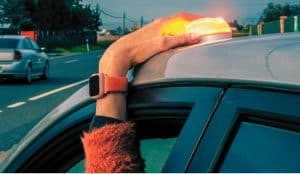 Baliza V16 homologada emitiendo luz de emergencia sobre un vehículo detenido.